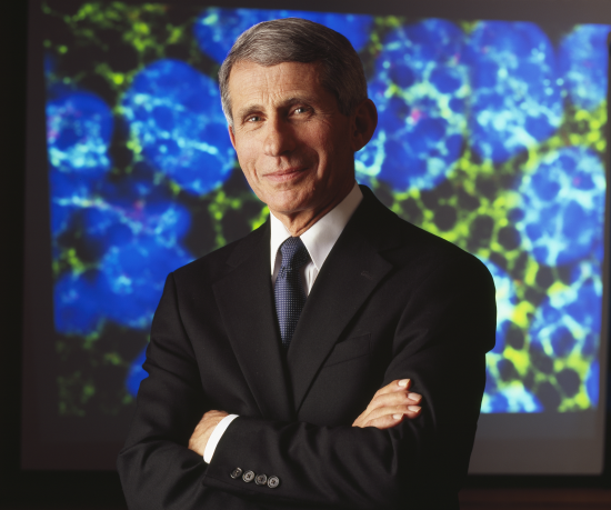 Dr. Anthony Fauci stands in front of a blue background