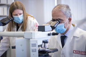 Kamel Khalili, PhD and Tricia H. Burdo, PhD looking into a microscopes in a lab